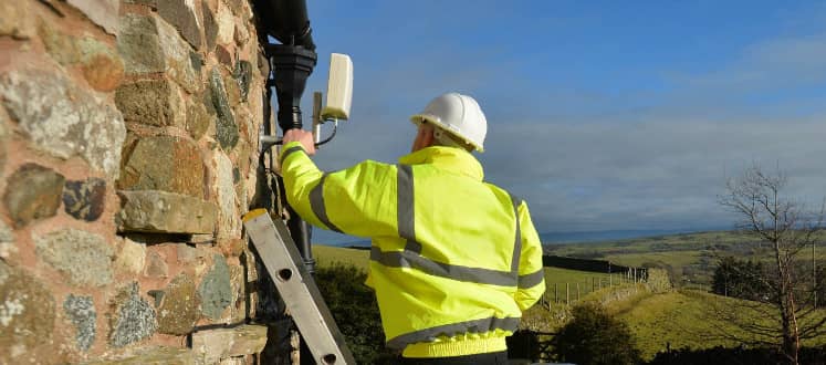 An engineer installing an antenna on a building